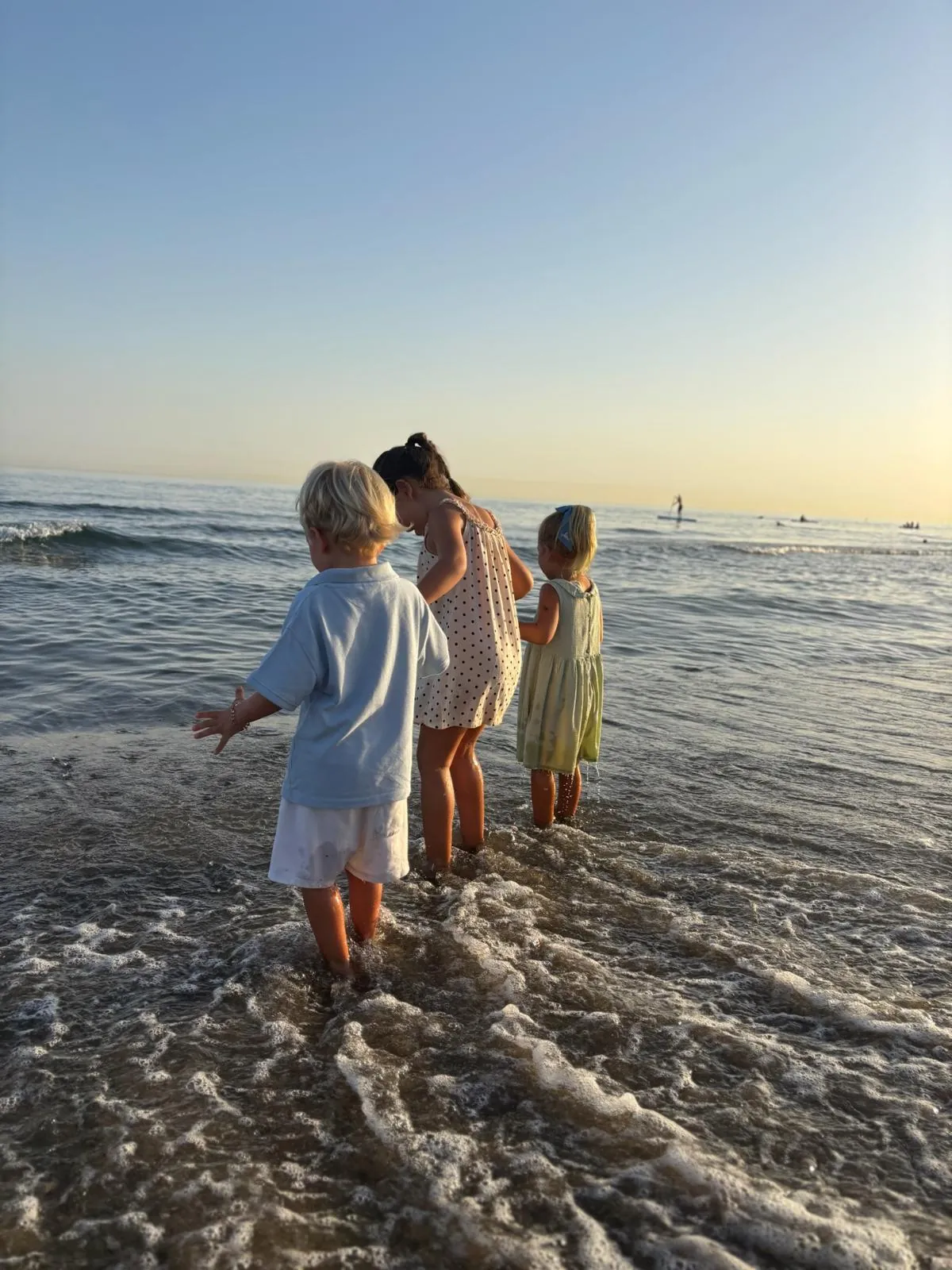 Children paddling at the water’s edge.