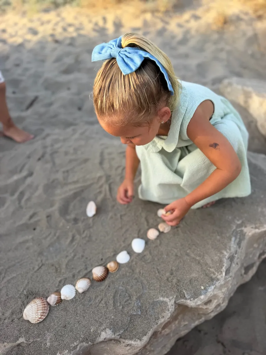 A child laying out shells in the sand.